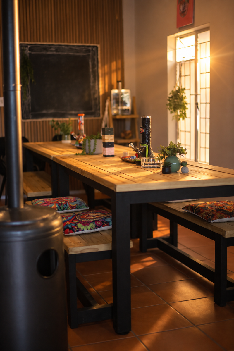 Sunlit wooden tables, plants and colourful cushions inside Herb Heaven