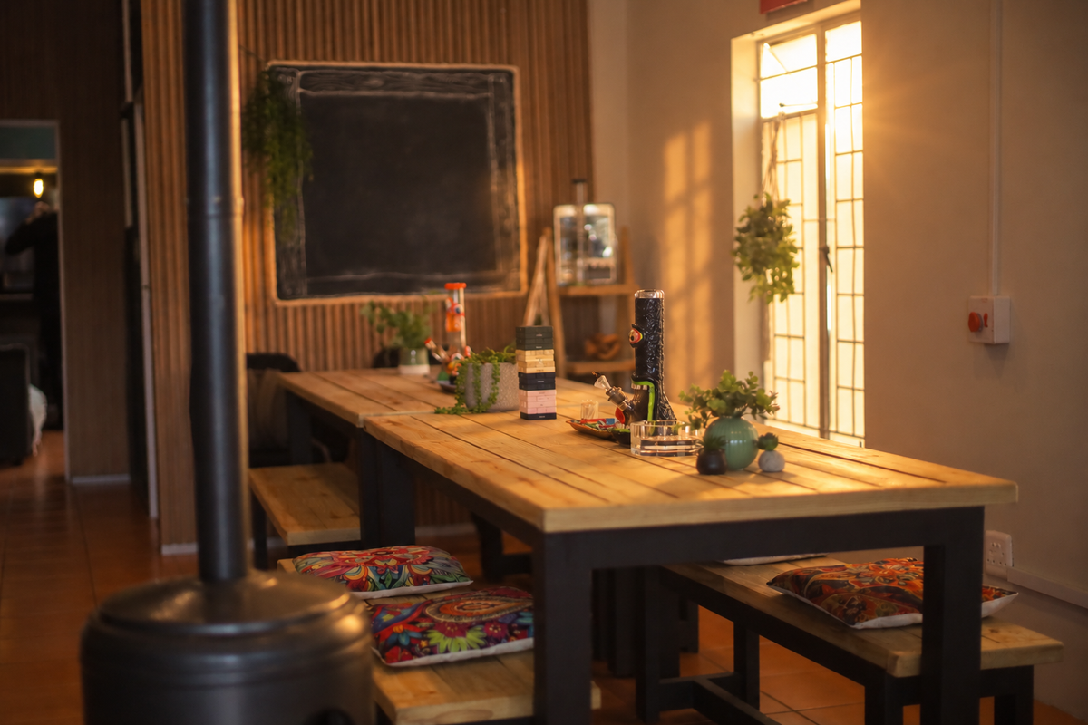 Sunlight across the communal wooden table and colourful cushions at Herb Heaven